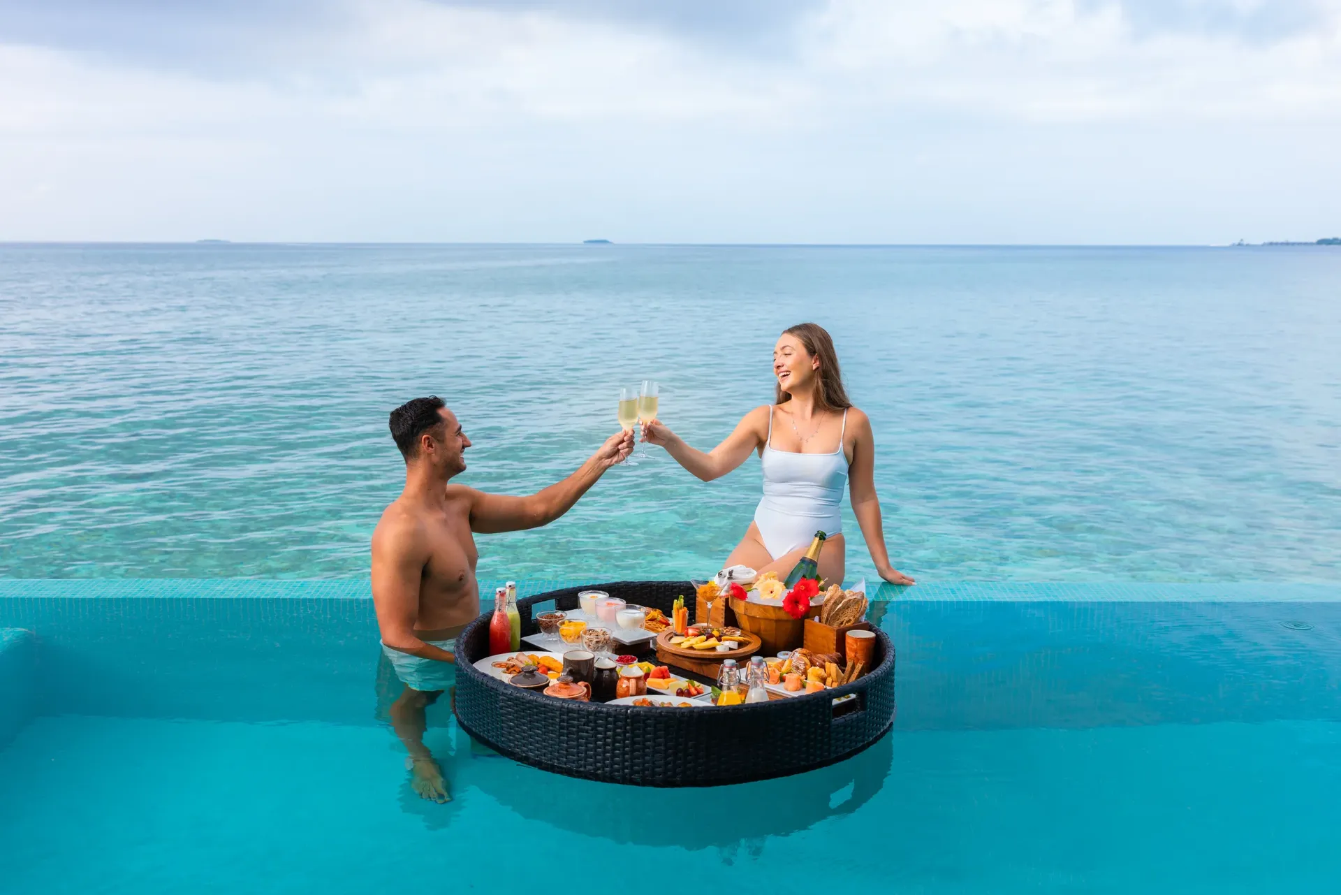 Couple with a floating breakfast in their villa pool